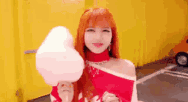 a woman with red hair is holding a cotton candy in her hand .