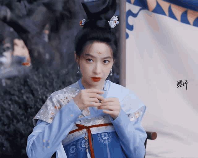 a woman in a blue and white dress with chinese writing on the bottom right corner