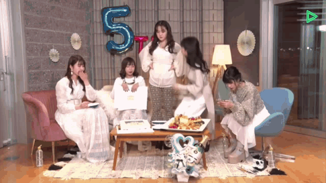 a group of women are gathered in a living room with a balloon that says 5 on it