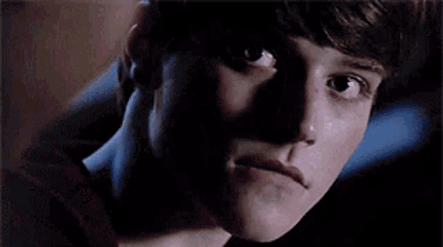 a close up of a young man 's face with a shadow behind him .