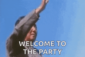 a man is standing in front of a blue sky with his arms in the air and saying `` welcome to the party '' .