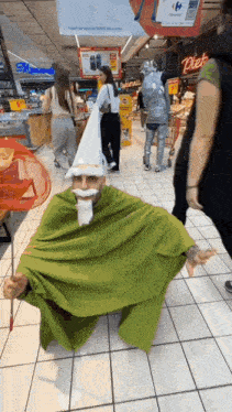 a man in a green cape and a white hat is sitting on the floor of a store