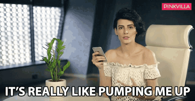 a woman sitting in a chair holding a cell phone with the words " it 's really like pumping me up " above her