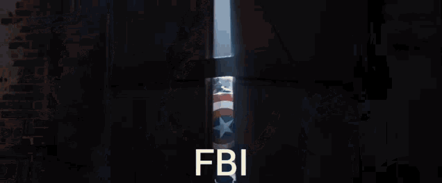 a group of men are standing in a dark room holding a shield with the word fbi written on it .