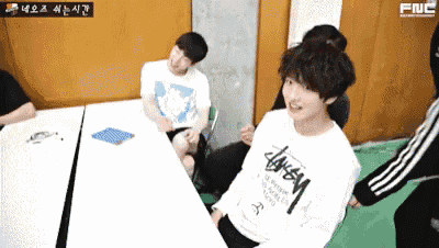 a man wearing a stussy shirt is sitting at a table