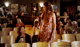a woman in a red dress stands in front of a crowd of people in a theater with a family.com logo on the bottom right