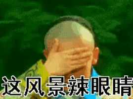 a man with a shaved head covering his face with his hands