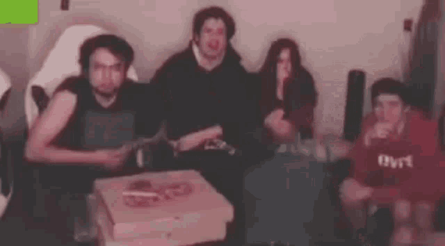 a group of people are sitting in a living room with pizza boxes .