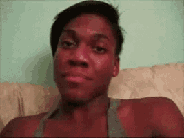 a man is sitting on a couch making a funny face and looking at the camera .