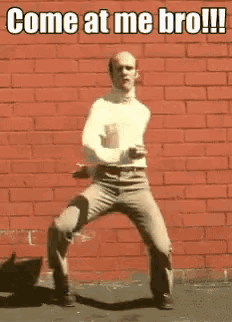 a man is dancing in front of a red brick wall with the words come at me bro