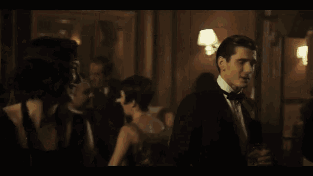 a man in a tuxedo stands in a crowd of people dancing