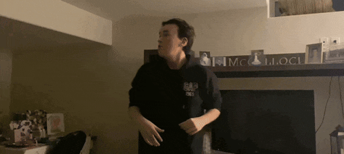 a man in a gap hoodie stands in front of a fireplace in a living room