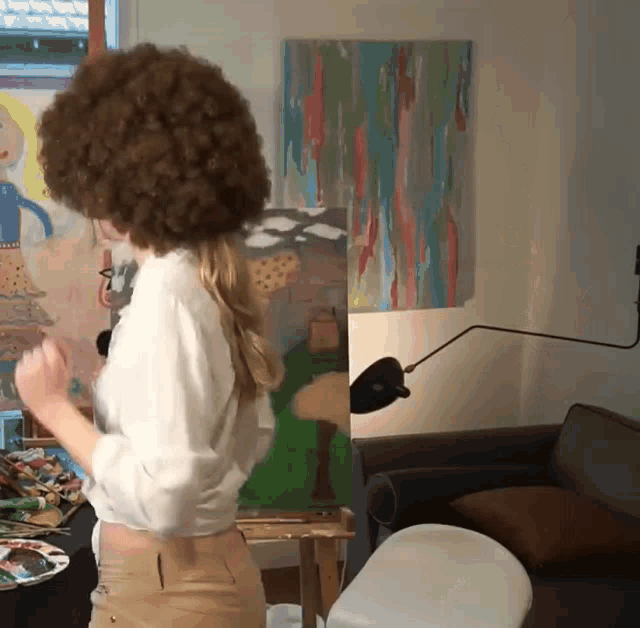 a woman with a large afro is painting a picture