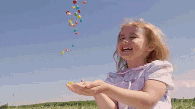 a little girl is holding jelly beans in her hands and laughing