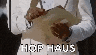 a man in a suit is holding a piece of paper with the words `` hop haus '' on it .