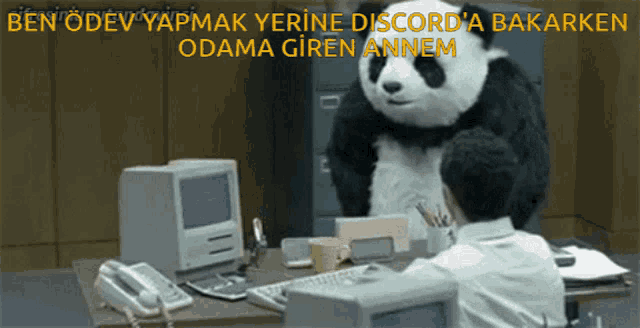 a man sitting at a desk with a stuffed panda bear standing behind him