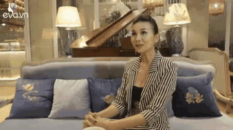 a woman in a striped jacket is sitting on a couch with pillows .