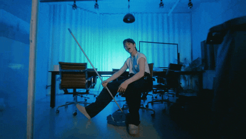 a man is sitting in a chair holding a mop in his hand
