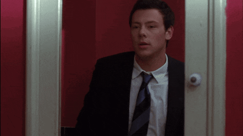 a man in a suit and tie is standing in front of a door