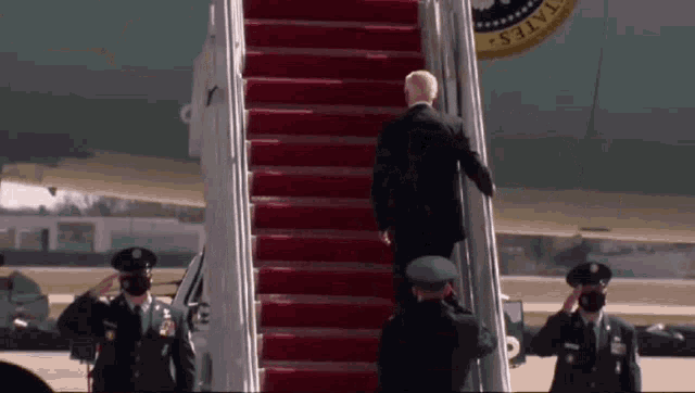 a man climbs the stairs of an airplane with a united states seal on the side