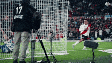 a man wearing a coca cola shirt is standing in front of a soccer net