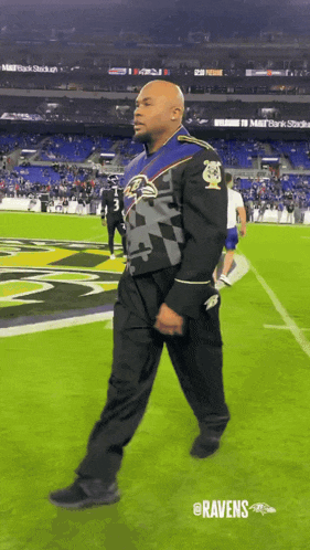a man in a ravens uniform walks across a football field