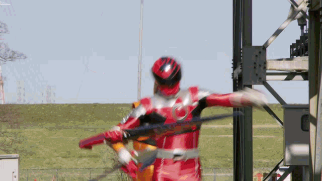 a man in a red superhero costume holds a sword