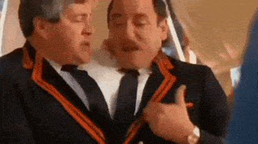 two men in suits and ties are standing next to each other on a plane .