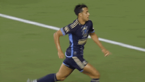 a soccer player is laying on the ground with his legs crossed while other players look on