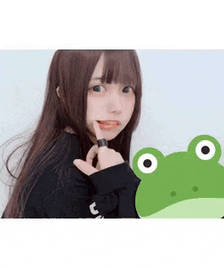a girl with long hair is standing next to a green frog and making a funny face .