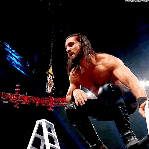 a shirtless wrestler is standing on a ladder holding a trophy .