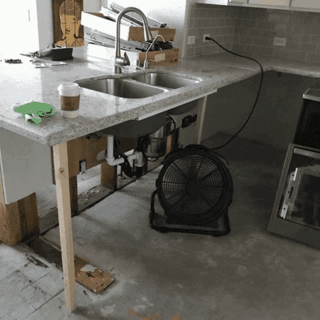 a kitchen counter with a sink and a fan on it