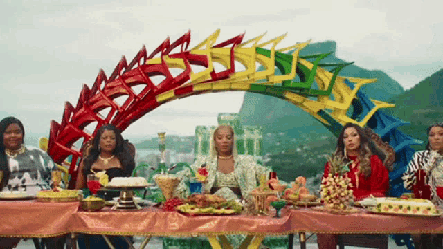 a group of women sitting around a table with food
