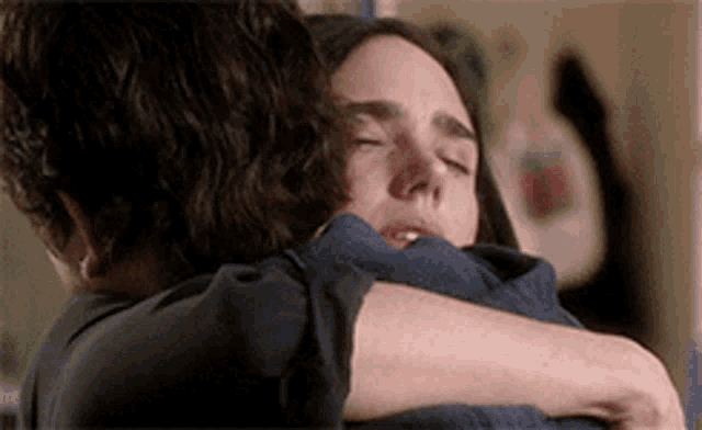 a man and a woman hugging each other with their eyes closed