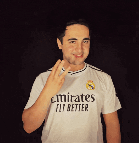 a man wearing a white emirates fly better shirt giving the peace sign