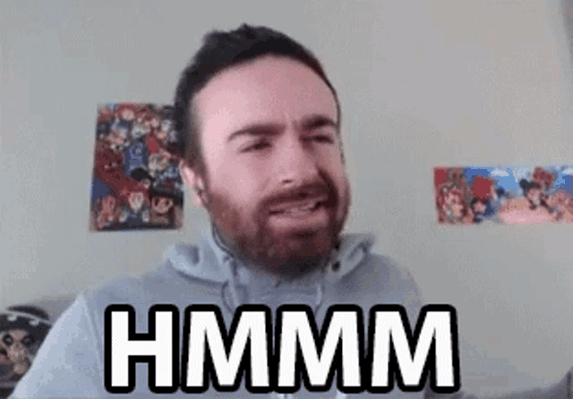 a man with a beard is making a funny face in front of a wall with posters on it .