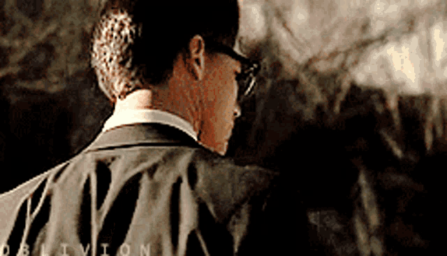 a man wearing glasses and a suit has the word oblivion on his back