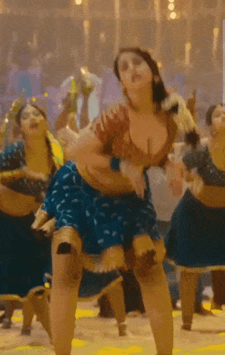 a woman in a blue skirt is dancing in front of a crowd of people