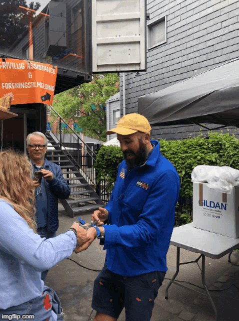 a man in a blue jacket is giving a woman a gift