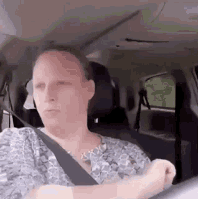 a woman is sitting in a car wearing a seat belt .