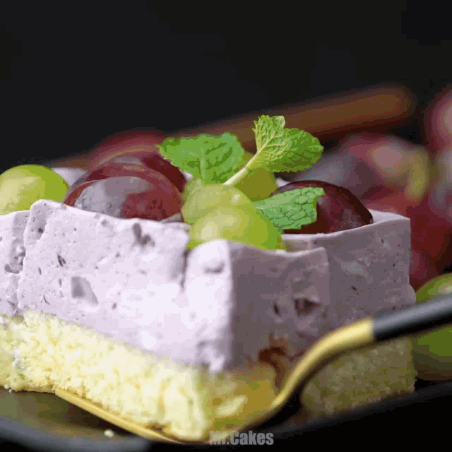 a piece of cake with grapes and mint leaves is on a plate with the words mr.cakes below it