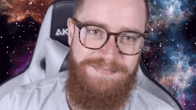 a man with glasses and a beard is sitting in a chair that says ak on it