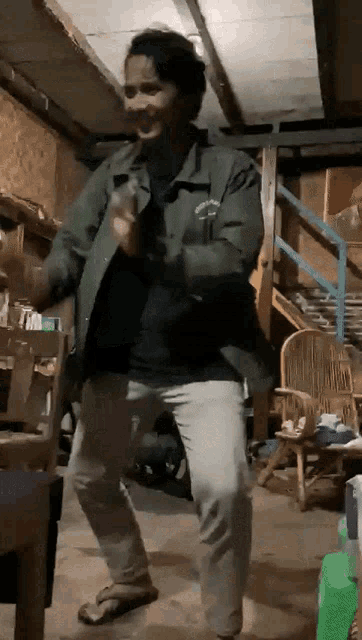 a man in a green jacket is dancing in a warehouse