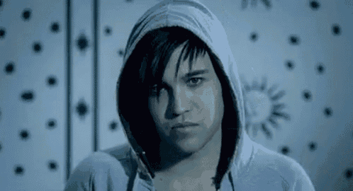a young man wearing a hooded sweatshirt is standing in front of a wall .