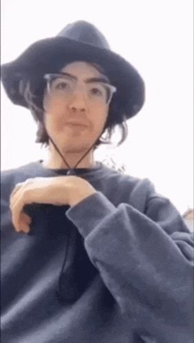 a man wearing a hat and glasses is taking a picture of himself