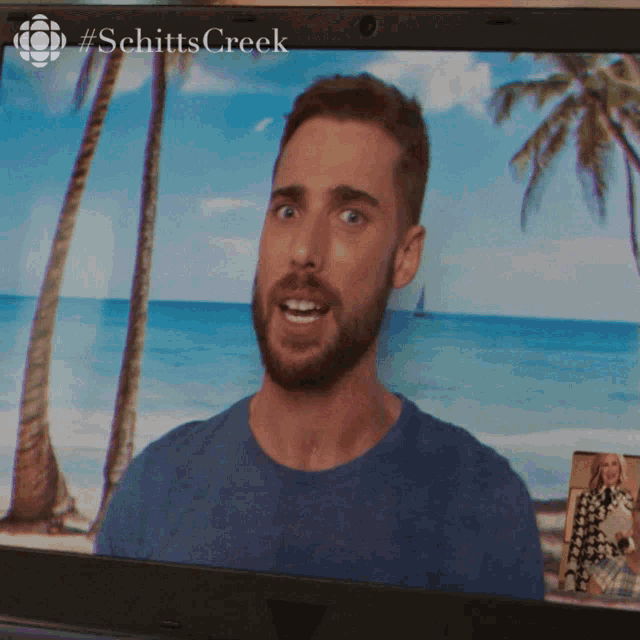 a man with a beard is on the screen of a laptop with #schitts creek written on it