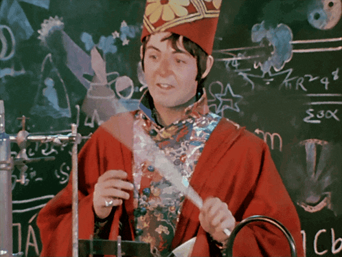a man in a red robe is standing in front of a chalkboard with the letters e and o on it