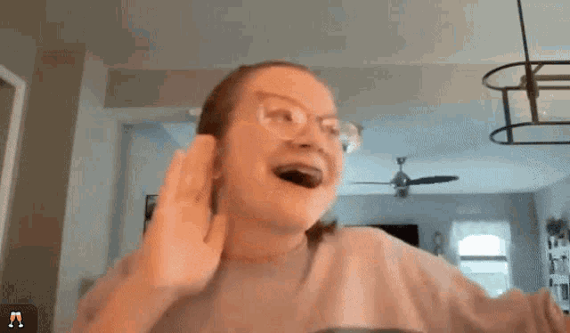 a woman wearing glasses is giving a high five in front of a ceiling fan