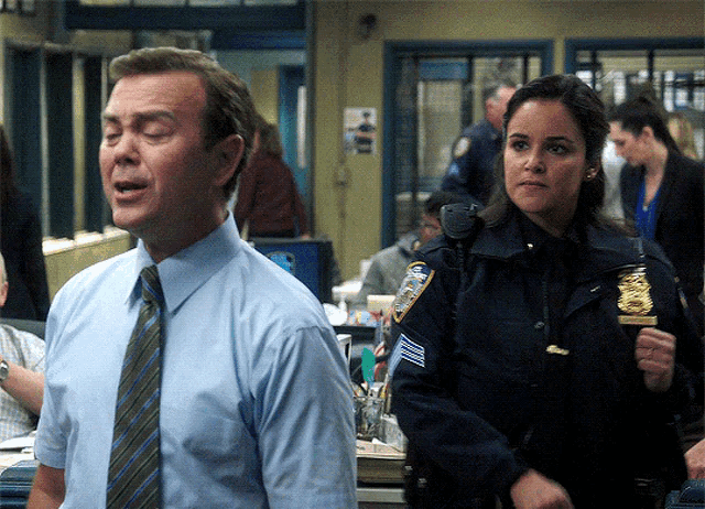 a man in a blue shirt and tie stands next to a woman in a blue uniform