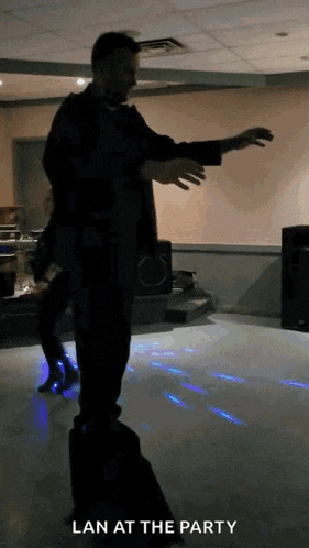 a man is standing on a suitcase on a dance floor with the words lan at the party above him
